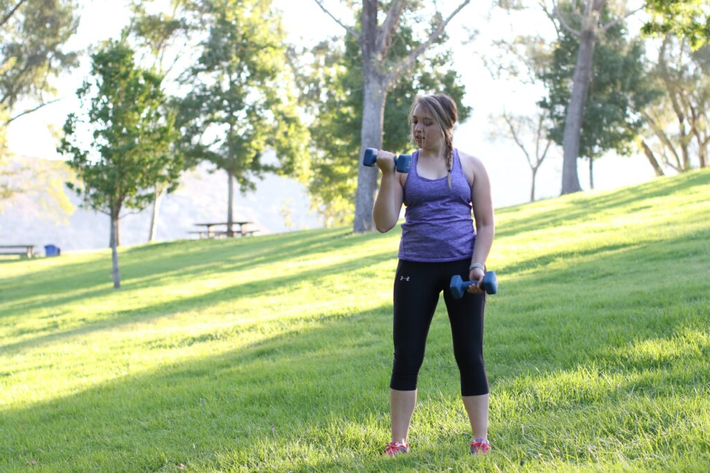 Woman lifting a dumbbell with one arm while holding the other pair on her side