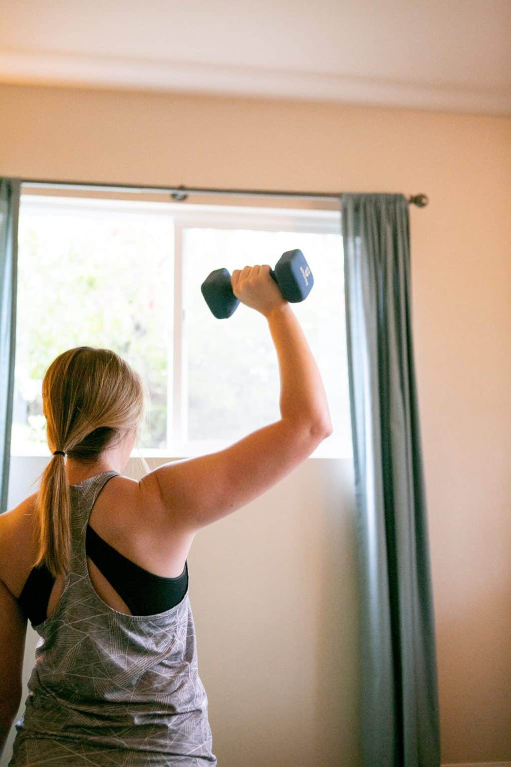 Back view of a woman lifting a 2kg dumbbell with one hand