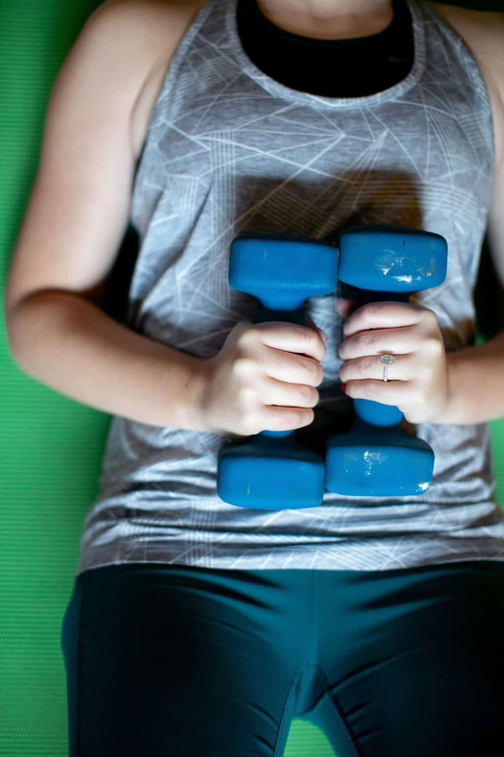 Woman lying on her back while holding two dumbbells on her stomach