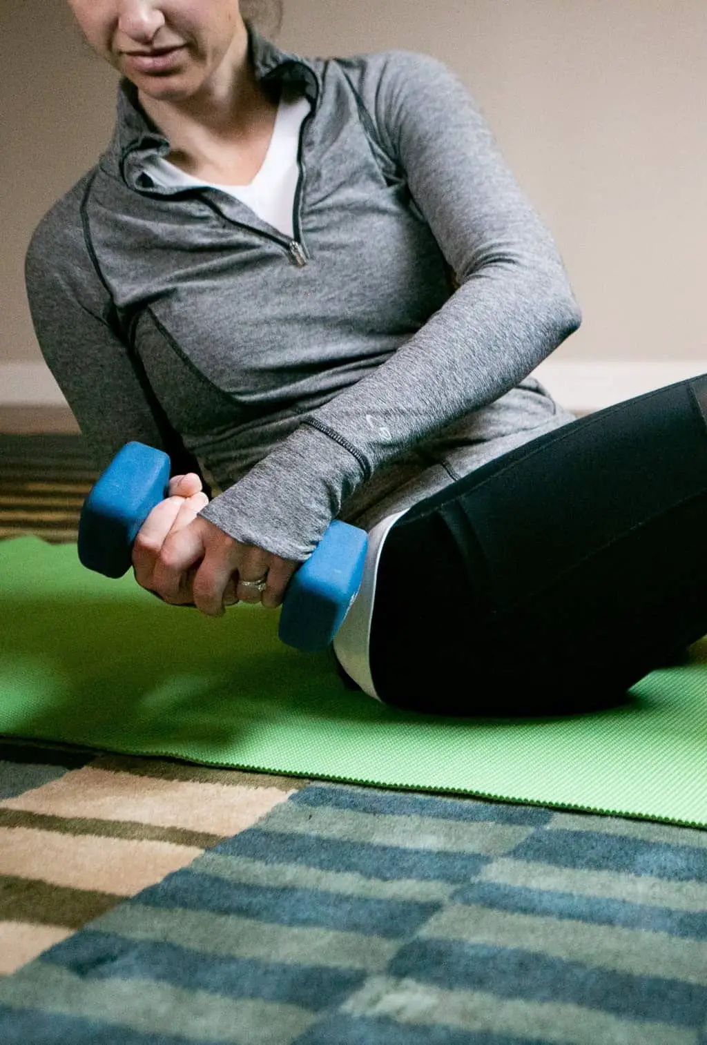 Woman sitting down while holding a dumbbell sideways