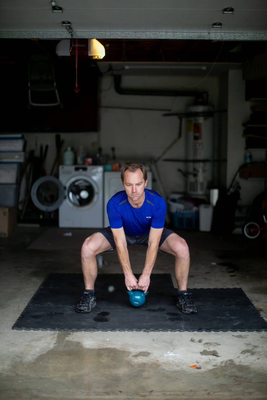 Man trying to lift a heavy kettlebell from the floor with both hands