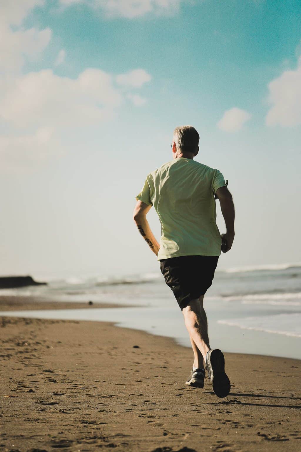 Un anciano trotando en la playa