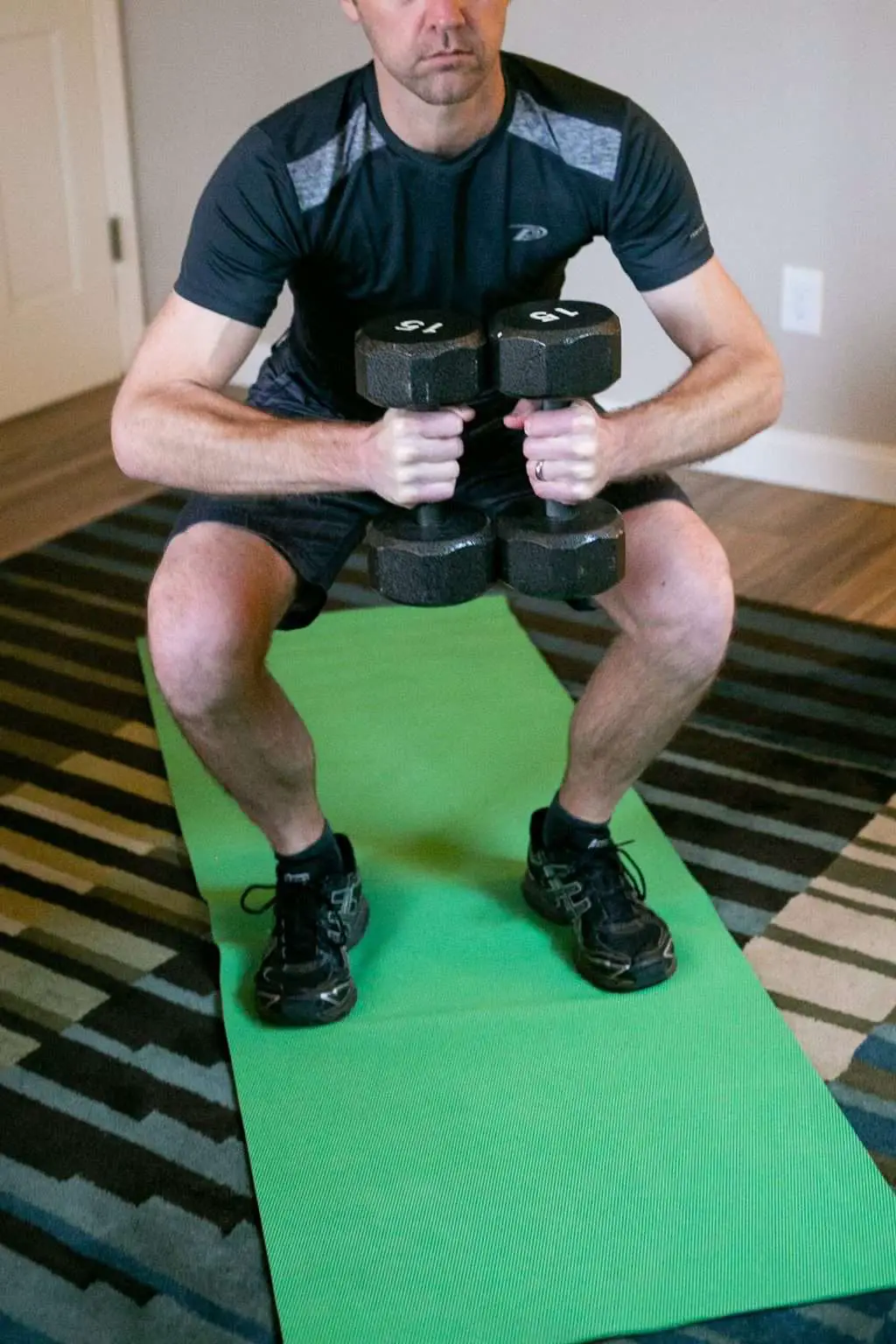 Man doing squats while holding dumbbells with each hand